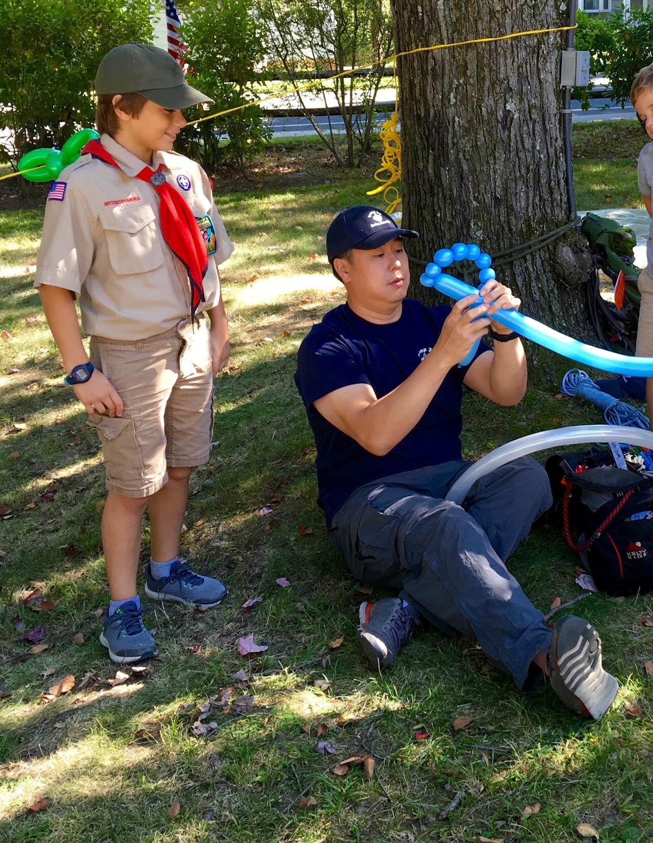 A balloon artist making a blue balloon animal outdoors